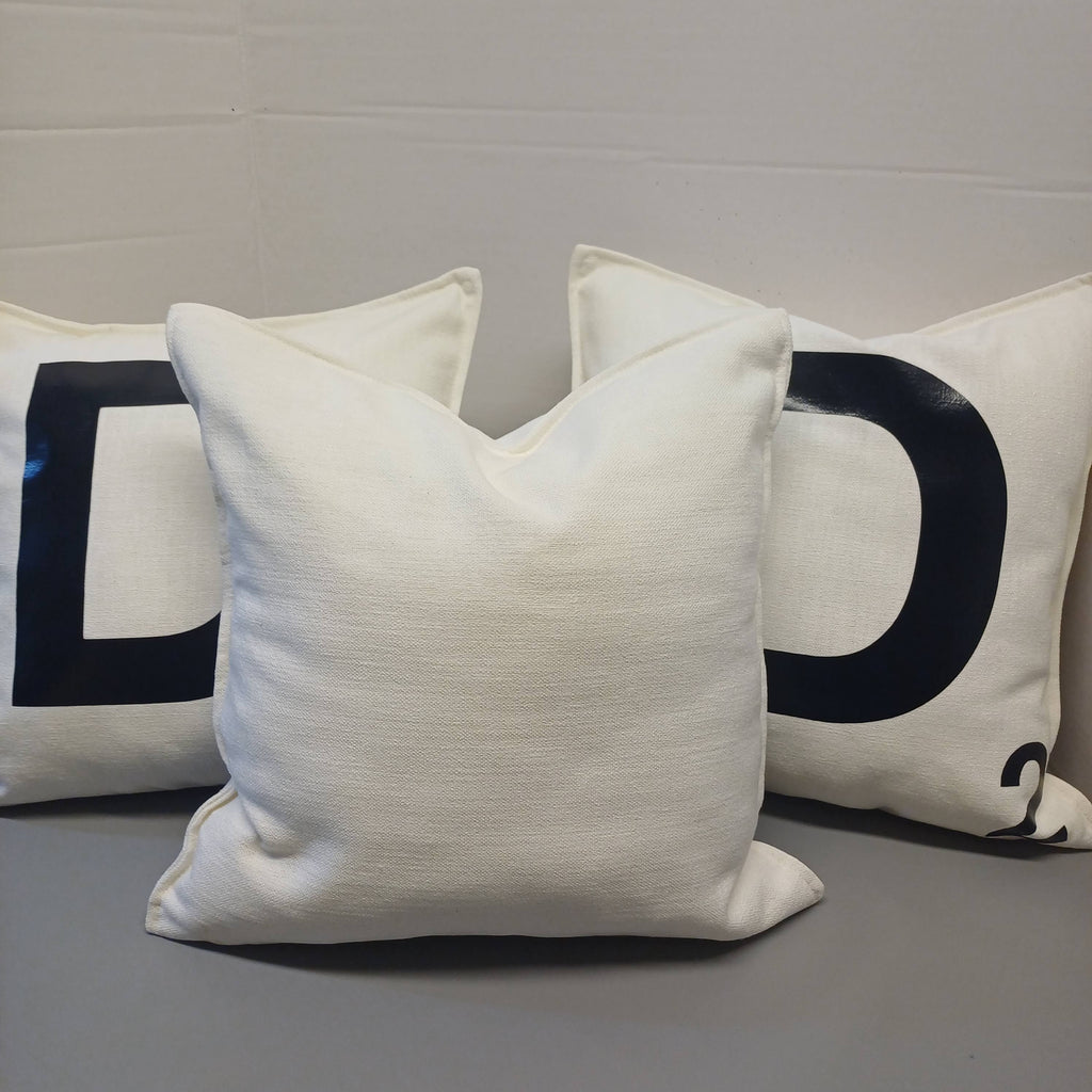 Three white pillows with black letters on a gray surface