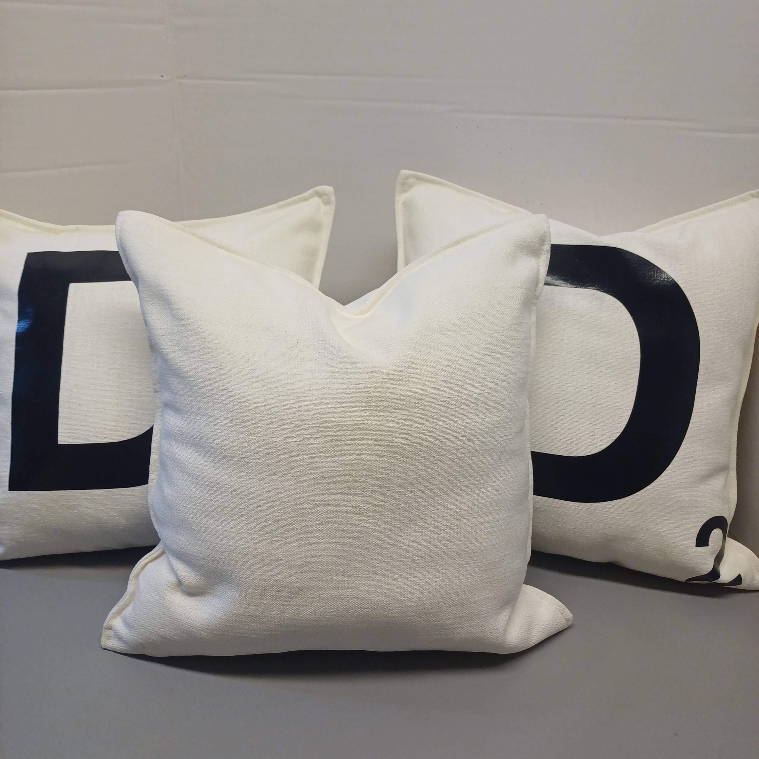 Three white pillows with black letters on a gray surface
