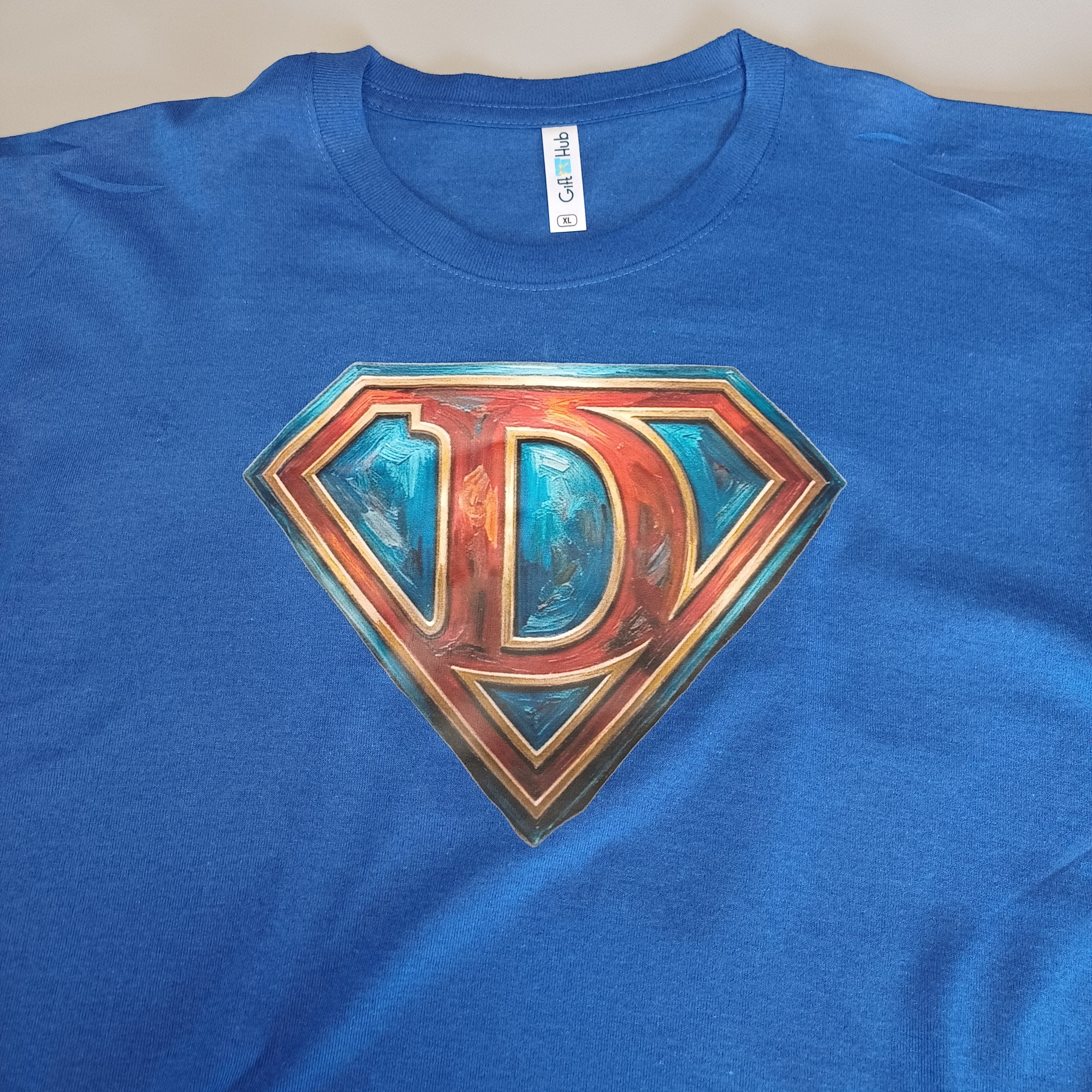 Blue t-shirt with a stylized 'D' logo on a plain background
