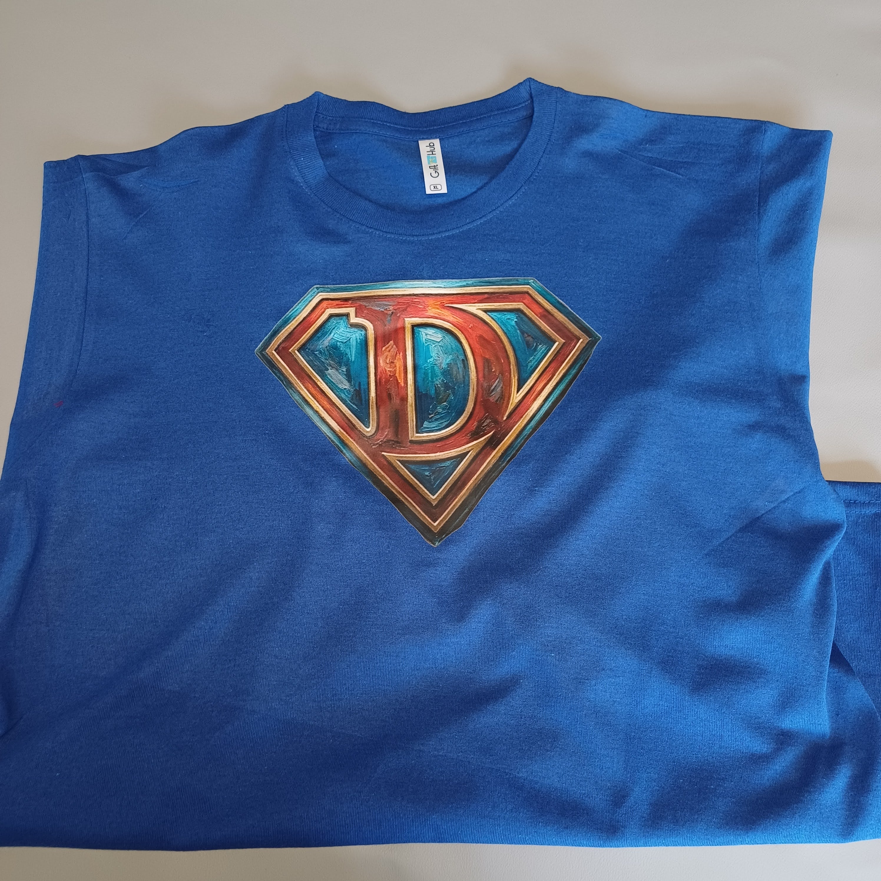 Blue t-shirt with a metallic 'D' logo on a plain background